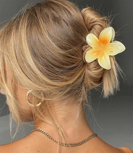 Macro view of gradient yellow plumeria hair claw clip worn on blonde hair