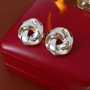 Gros plan de boucles d'oreilles nœuds argentées sur un écrin à bijoux en cuir rouge
