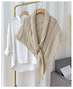 Detail of beige cable-knit triangle shawl with brown leather buckle and hollow texture