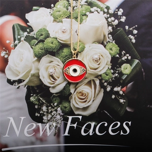 Macro shot of evil eye pendant with red enamel on a gold chain with white roses
