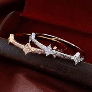 Macro shot of 18K gold and silver plated bangles with star texture on black velvet