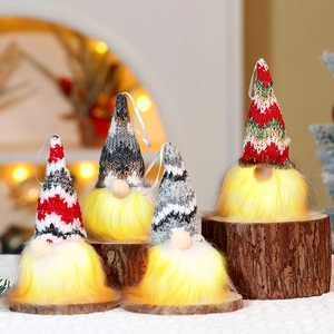 Close-up of four glowing Christmas gnomes on wood base with warm festive background