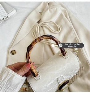 Detail of bamboo handle and marble pattern flap on retro woven crossbody straw bag