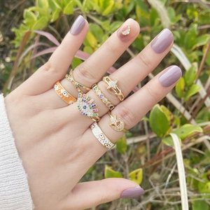 Macro shot of gold-plated rings with colorful zircons, evil eye and star moon designs