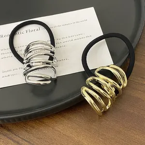 Detail of silver and gold irregular streamline metal hair ties on black tray