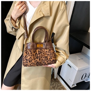 Detail view of leopard print bucket bag with brown leather trim and gold metal lock