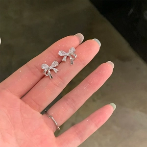 Detailed macro view of silver bow stud earrings with sparkling cubic zirconia inlay