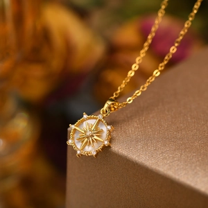 Elegant gold shell sun pendant necklace with sparkling zircon starburst on a gift box