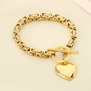 Macro shot of gold stainless steel Byzantine chain with heart charm and toggle clasp