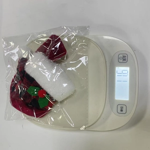 Detailed view of plaid Christmas wine bottle decoration on a scale weighing 11.6 grams