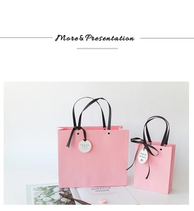 Pink gift bag set with black silk handles, ribbons, and Thank You tags in macro detail