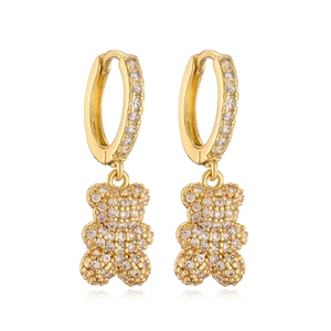 Golden teddy bear earrings with sparkling rhinestones on a white reflective background