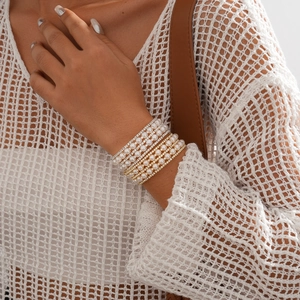 Detailed view of layered faux pearl and rhinestone bracelets on a female model