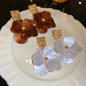 Macro view of flower earrings featuring brown amber and white shell acrylic petals