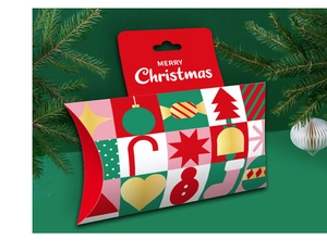 Close-up of Christmas pillow gift box with festive geometric patterns on green background