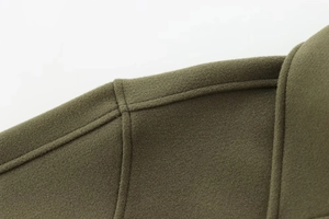 Détail macro de l'épaule d'un manteau en laine vert militaire avec coutures précises
