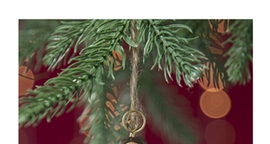 Detail of painted vintage angel ornament hanging on green pine branches with bokeh lights