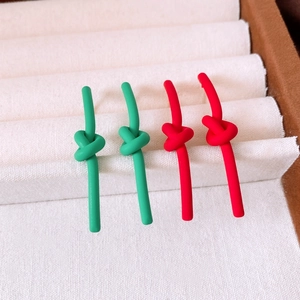 Detail view of red and green knotted stud earrings with a matte spray paint finish