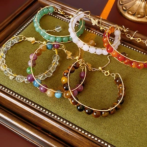 Macro detail of multi-color gemstone beads with golden wire wrap and butterfly charms