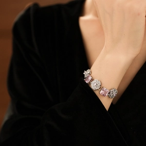 Detail of a silver bracelet with pink square gemstones and zircon flowers on a wrist