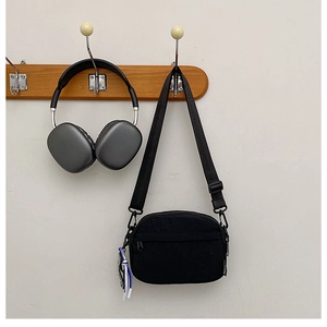 Détail du sac bandoulière léger en nylon noir avec sangle réglable et pendentif en corde