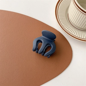 Detail der matten marineblauen Haarklammer auf Ledermatte mit schickem Kaffeetassen-Hintergrund