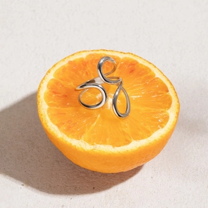 Artistic display of a silver geometric curved ring placed inside a fresh orange slice