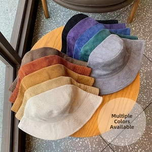 Vue à plat de chapeaux bobs en velours côtelé de dix couleurs sur une table en bois