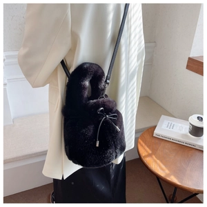Detail of black faux fur bucket bag with drawstring bow on an elegant model