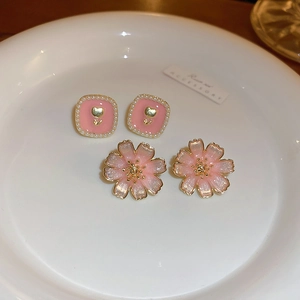 Detail of pink floral and pearl square studs with heart pattern on white ceramic plate