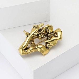 Artistic gold lovers embrace brooch with abstract face sculpture on white geometric stand