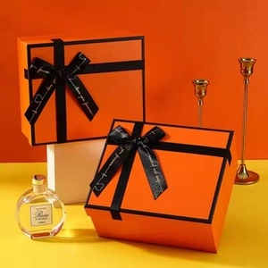 Detail of square orange gift box with black ribbon bow and elegant window lid design