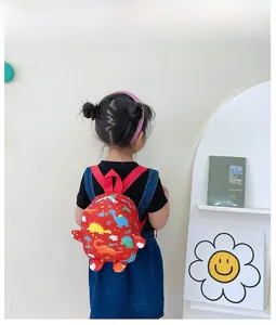 Detail view of red children backpack with colorful cartoon dinosaur prints and red straps