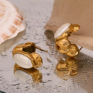 Vue macro de boucles d'oreilles plaquées or 18K avec incrustation de nacre et gouttes d'eau