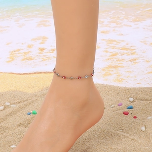 Close-up of a silver beaded anklet on a beach setting with sea waves background