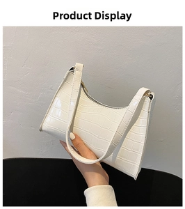 Close-up of white crocodile pattern shoulder bag with golden zipper and sleek handle