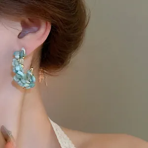 Elegant silver needle C-shaped earrings with light blue beads and gold accents worn by a model