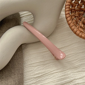 Pink duckbill hair clip on artistic stand with warm minimalist lifestyle background
