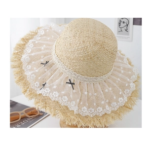 Détail d'un chapeau de paille avec broderie florale en dentelle et nœuds en soie noire