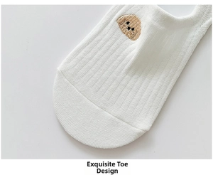 Detail of white cotton no-show sock featuring cute brown dog embroidery and ribbed texture