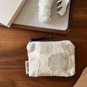 Detailed close-up of a beige textured cotton linen pouch with simple wish brand tag