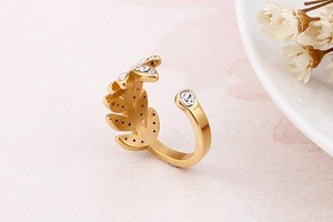 Macro d'une bague feuille dorée avec zircons sur fond de marbre rose élégant