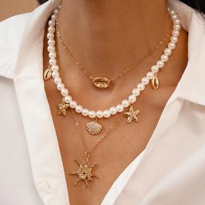 Detail view of a 3-layer necklace set with pearls, starfish, and shell pendants