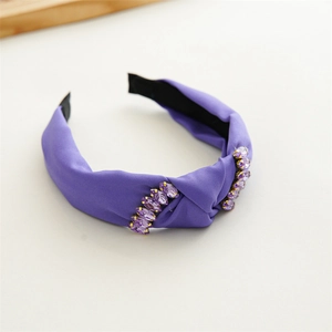 Detailed view of purple fabric headband with sparkling crystal rhinestones on white background
