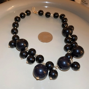 Close-up of black oversized irregular beaded necklace with golden metal hardware