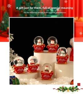 Close-up of Santa and Snowman crystal snow globes with red sleigh-shaped resin bases