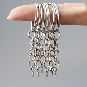 Silver metal keychain parts held by hand showing ring, chain, and eye screw detail