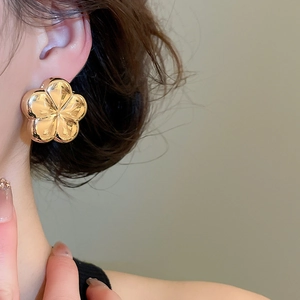 Close-up of elegant gold 3D flower stud earring with polished metallic finish on ear
