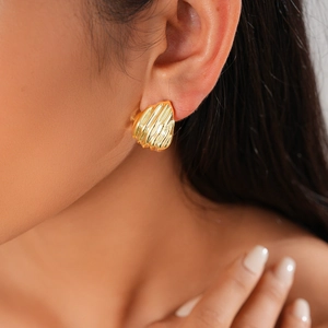 Gros plan détaillé d'une boucle d'oreille dorée en forme d'éventail sur un modèle