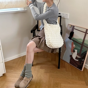 Minimalist white bubble textured tote bag shown on a model in a cozy lifestyle setting